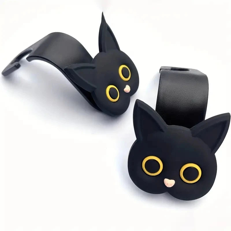 Pair of black 3D cat headrest hooks with yellow-ring eyes and curved straps