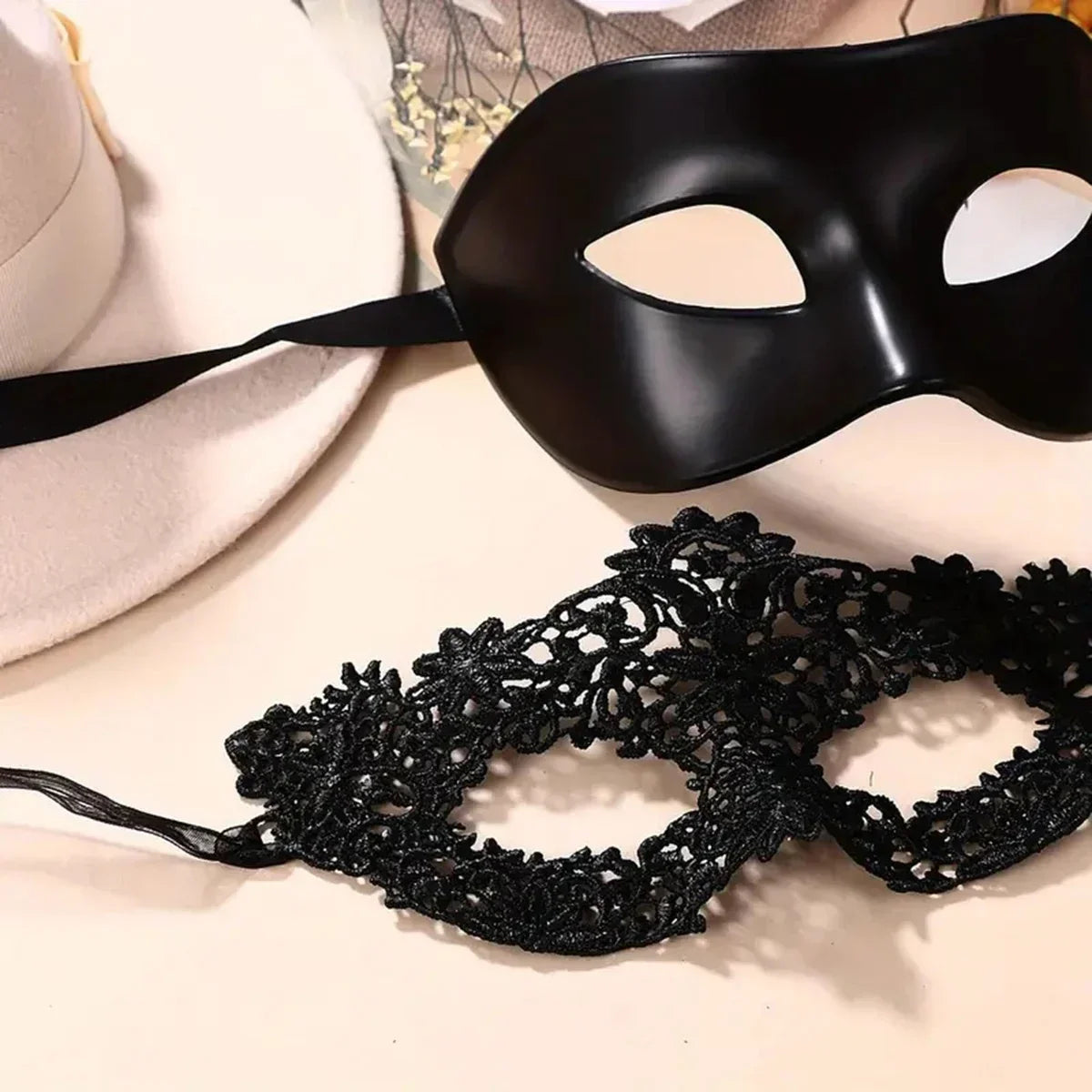 Black molded eye mask and black lace eye mask lying flat with ribbon straps