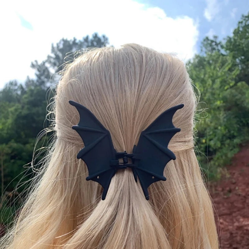 Black bat hair clip with spring clasp and pointed wings, worn in blonde hair