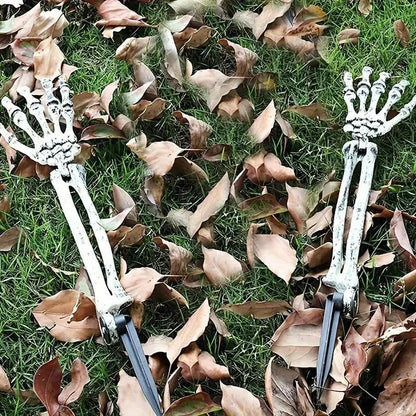 Skeleton hand garden stakes scattered in fallen leaves on green grass