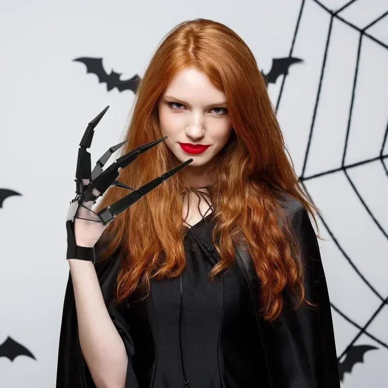 Black articulated finger claw glove held up near face with long pointed claws