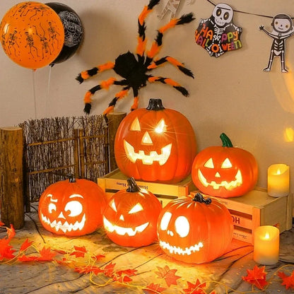 Glowing orange LED pumpkin lanterns with carved jack-o'-lantern faces on an outdoor table