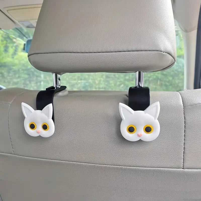 Set of 2 white cat headrest hooks with yellow eyes mounted on seat back