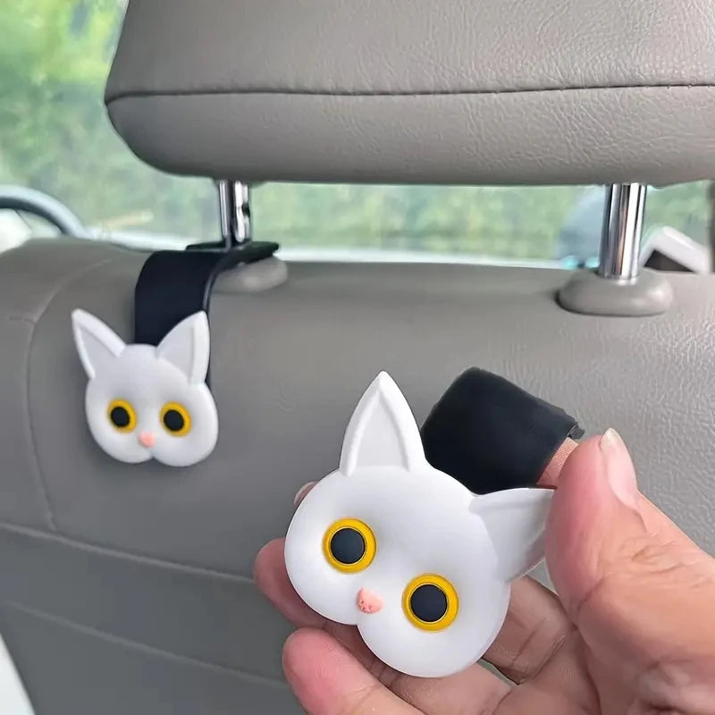 White cat headrest hook pair with 3D cartoon face, shown held for mounting