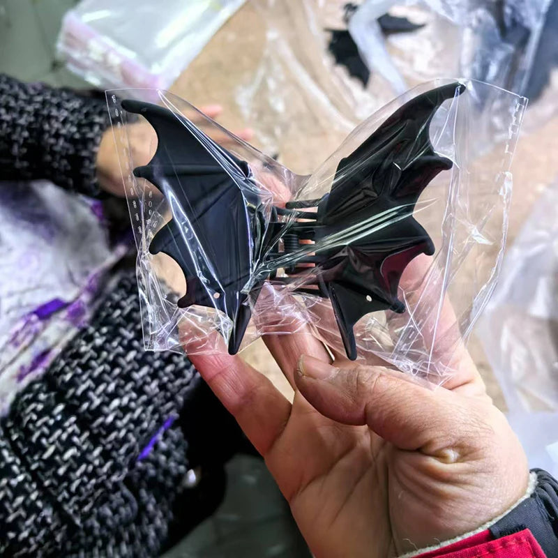Black bat hair clip with pointed wings and spring clasp, in clear packaging