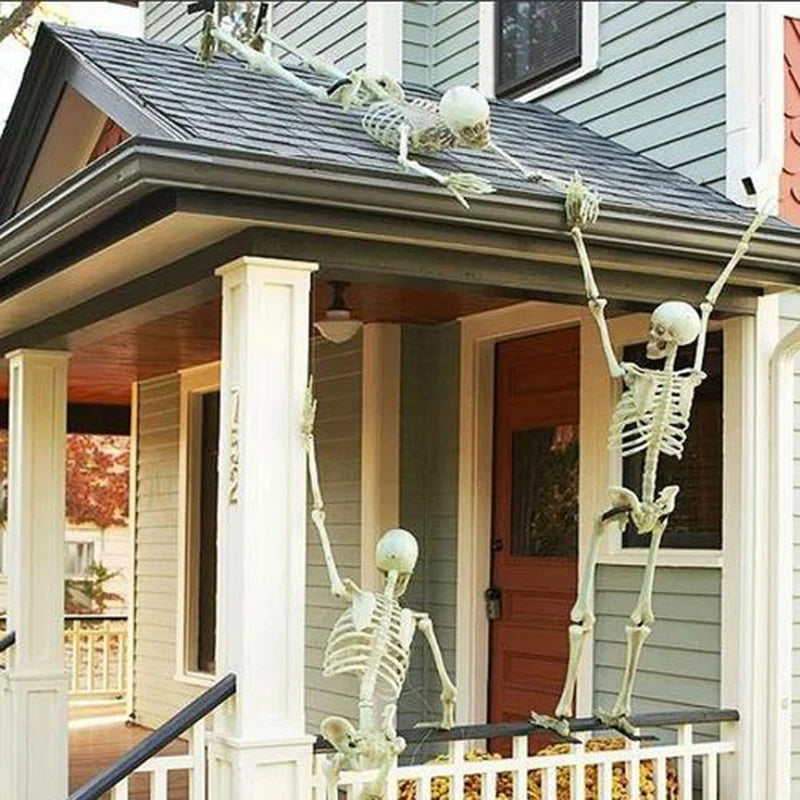 Several small white skeleton props on a front porch railing for Halloween