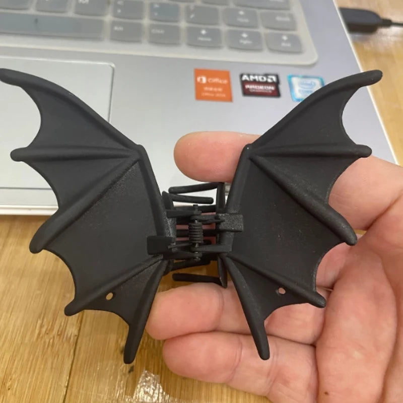 Black bat hair clip with metal spring and pointed wings, held in hand
